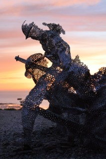 Life size sculptural figure in the D-Day 75 Garden in Arromanches-les-Bains, France at Sunset. The installation was first created by John Everiss for