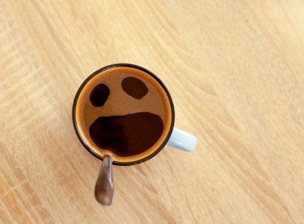 Coffee cup with funny screaming in fear face, top view. Open crying mouth in mug on table background. Shocked, stressed, angry, scared and furious foa