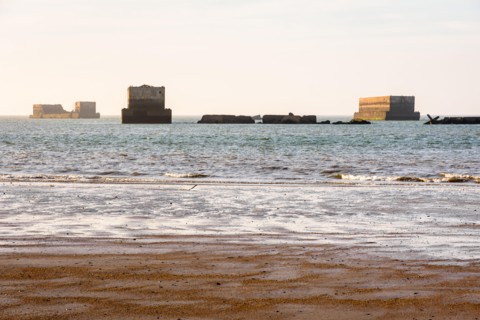 Remains of Phoenix caissons used to build the artificial Mulberry harbour on Gold Beach in Arromanches, France, after the Normandy landings in WWII.
