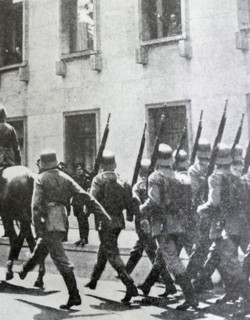 Black and white photo of soldiers marching down a street in Berlin, on the morning after the Night of the Long Knives (30 June 1934).