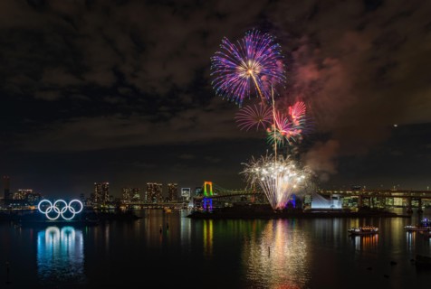 A picture of the fireworks commemorating the opening of the Olympic Rings in the Tokyo Bay, featuring the Rainbow Bridge, at night (Tokyo).
