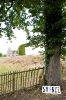 The destroyed French village Oradour-sur-Glane. It's entrance has a sign requesting silence resting against an oak tree.