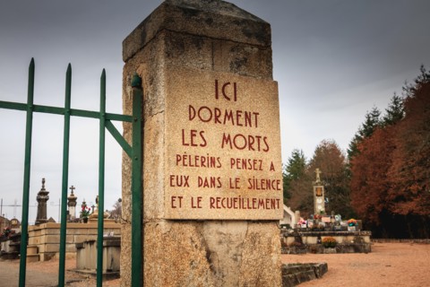 ORADOUR SUR GLANE, FRANCE - December 03, 2017 : at the entrance of the cemetery a stone plaque where it is written - here sleep the dead pilgrims thin