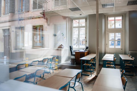View from the street of large school classroom with empty seats - reflections of city in the window