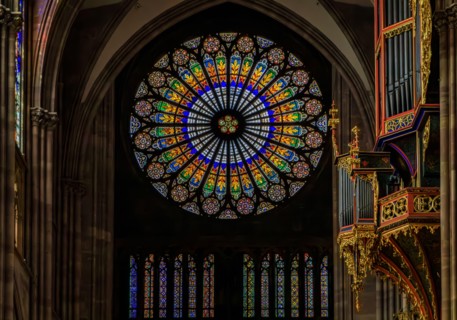 Strasbourg, France - June 3, 2023: Ornate stained glass rose window and organ in the beautiful Gothic cathedral of the Notre Dame, historic center