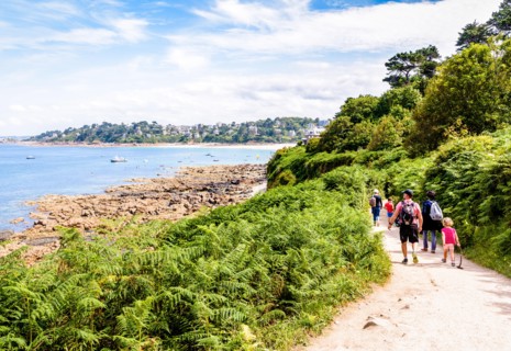A family with children is walking towards Perros-Guirec on the "sentier des douaniers", the GR34 coastal path along the Pink Granite Coast in Brittany