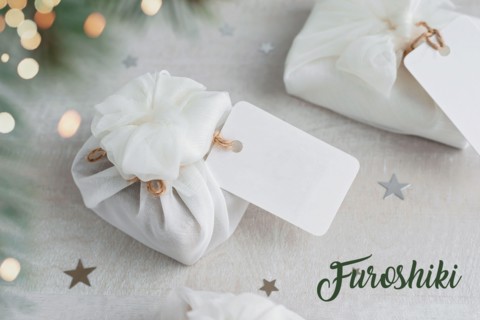 Christmas present wrapped with white furoshiki fabric with labels. Eco friendly gift.
