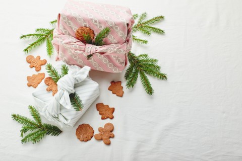 Christmas eco-friendly gift wrap in traditional japanese furoshiki style decorated with fir twigs and gingerbread cookies on fabric background, eco-fr