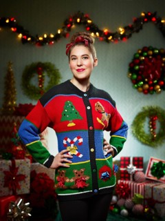 Portrait of woman in ugly Christmas sweater looking into camera with pride