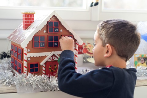 young caucasian boy looking for a surprise in the advent calendar at home