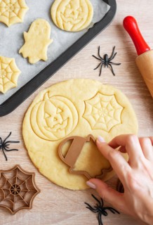 Preparation of festive cookies for baking in the oven. Ready-to-bake Halloween cookies shaped like pumpkins and ghosts