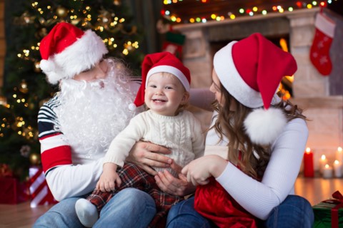Happy family with child son having a fun near Christmas tree and fireplace  in living room