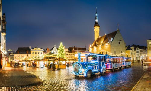 Beautiful Train for sightseeing near Traditional Christmas Market On Town Hall Square - Raekoja Plats In Tallinn, Estonia. Christmas Tree And Trading