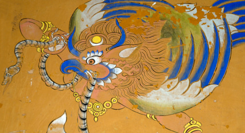 Mural of a Garuda painted in traditional Bhutanese style on a wall in Wangdichholing Dzong. It has a snake, naga, in its beak.