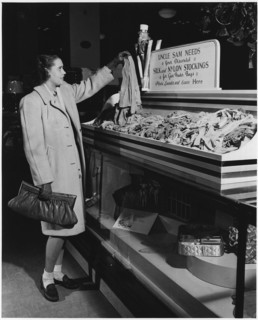 Part of a campaign to collect used nylon stockings for American efforts during World War II, a young woman holds up a pair of disbanded stockings that will be recycled into gun powder bags, 1942. Imag...
