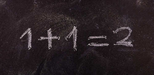 School maths concept. Math simple equation 1+1=2, isolated, on blackboard background.