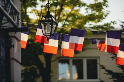 Shallow depth of field (selective focus) details with french flags at a garden party during the France 14th of July National Day.
