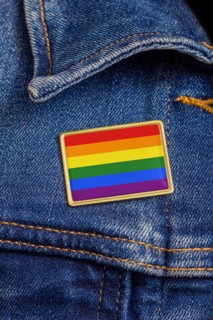 Gay pride flag pin on a denim jacket for LGBTQ identity, pride, and activism. The flag design is public domain for all uses.