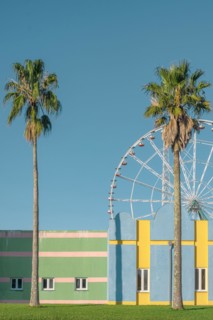 Building exterior minimal pastel colors and geometric lines with palm trees and ferris wheel on background. Abstract colorful architecture. Vertical o
