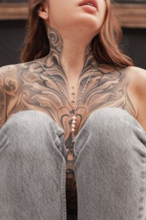 This image captures a close-up view of a womans chest area featuring an elaborate and artistic tattoo, highlighting the details and craftsmanship in n