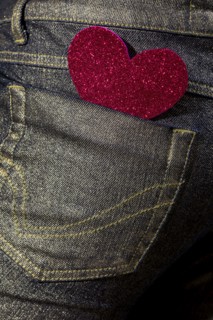 A vibrant red glitter heart-shaped sticker adorns the back pocket of a denim jean, symbolizing casual love and fashion
