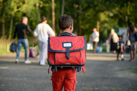 view of a child going to school with a schoolbag on his back on the first day of school in France