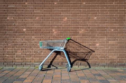 abandoned, empty supermarket trolley by a brick wall, shopping concept.