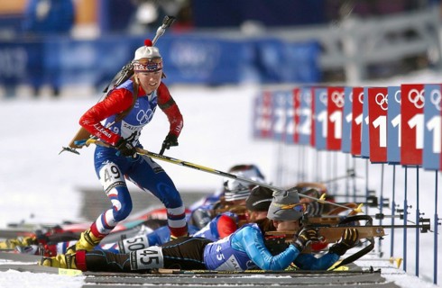 Competing in the Biathlon event, National Guard SPECIALIST (SPC) Kara Salmela, USA, with her .22 caliber, bolt-action rifle slung on her back, jumps from the prone position, skies in hand, leaves the ...
