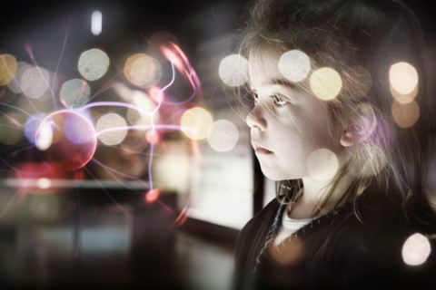 A small female child looking at a plasma ball