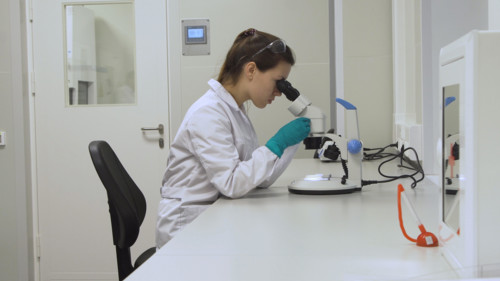 Doctor woman working a microscope. Female scientist looking through a microscope in lab. Student girl looking in a microscope, science laboratory concept