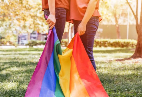 A lesbian female couple holding a LGBTQ rainbow flag, symbol for the homosexual community. Gay flag for pride month and the celebration day of sexual