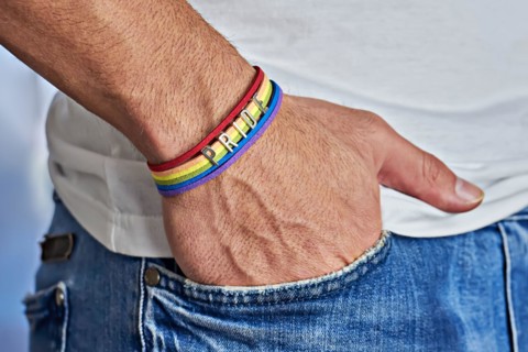 Male hand with rainbow bracelet and text pride in pocket of jeans. Freedom and LGBT concept