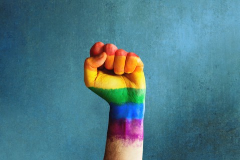Raised rainbow fist of a man for PRIDE month and the LGBTQIA+ movement. Pride day for sexuality freedom, love diversity celebration and the fight for