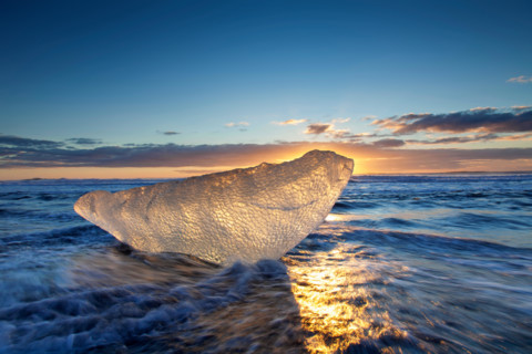 Melting block of ice washed on beach along the Atlantic Ocean coastline at Breidamerkursandur black sands in winter, Iceland