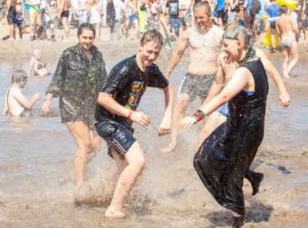Young people playing in mud pool during 21th Woodstock Festival Poland