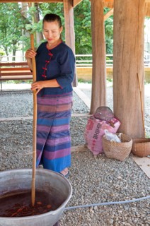A woman mixes assorted cocoa beans in a sauce to make chocolate