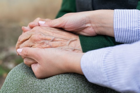 Close up picture of caregiver holding senior woman's wrinkled hands