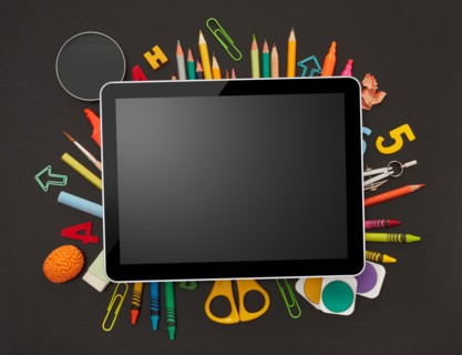 Digital tablet and school supplies on blackboard