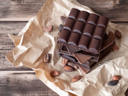 Chocolate bars and cocoa beans on the rustic background. Chopped pieces of dark and milk chocolate on wooden table