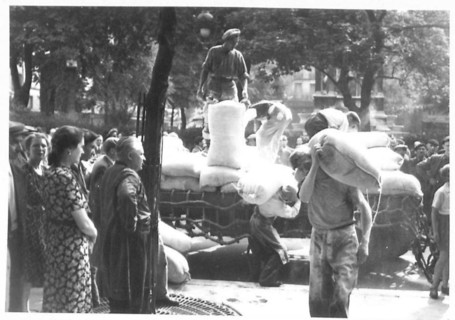 Parisians observe food supplied by the British being unloaded from lorries at the Les Halles market in Paris, British Army, 21st Army Group.