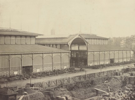Photograph showing pavilions of Les Halles, the central market of Paris, including outdoor vendors and new construction in the foreground. Paris. 1867