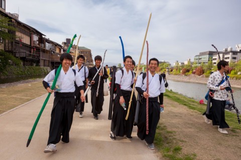 School boys carrying archery equipment, walk along the sides of the Kamo River in Gion, Kyoto, Japan.