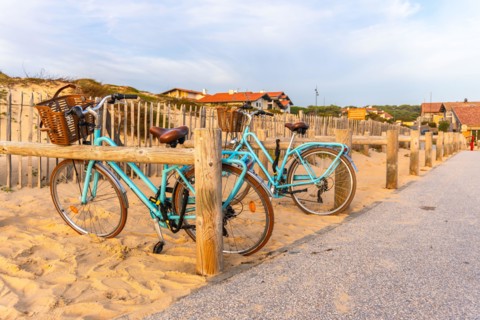 Blue bicycles parked on sand dune fence in seignosse
