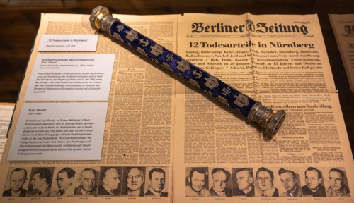 Hamburg, Germany - 7 Apr 25: Museum display featuring a Berliner Zeitung page about Nuremberg trial verdicts alongside a decorated admiral baton, Inte
