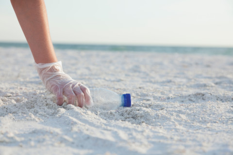 USA, Florida, St. Petersburg, Girl (10-11) cleaning beach, close-up of gloved hand reaching for plastic bottle