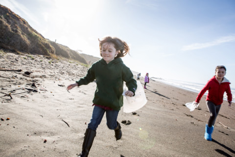 Girls picking up trash on beach cleanup day.