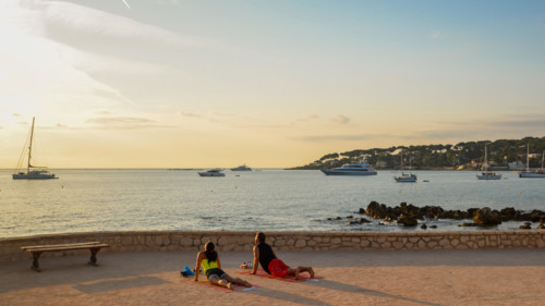 A man and a woman practice yoga early in the morning overlooking Antibes, Cote d'Azur, France