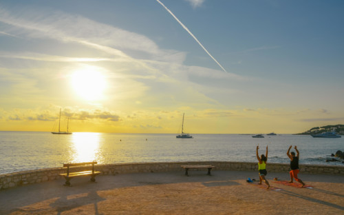 A man and a woman practice yoga early in the morning overlooking Antibes, Cote d'Azur, France