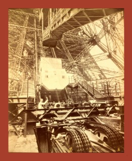 Eiffel Tower machinery with a man beside the wheel that raises elevator, during the Paris