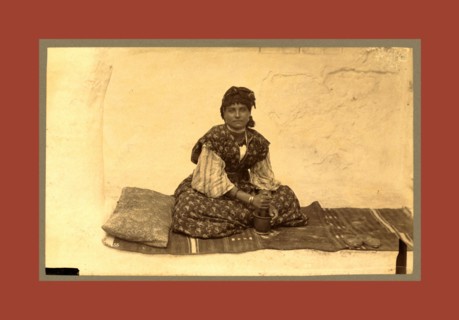 woman, full-length portrait, seated on rug on ground, facing front, using mortar and pestle,